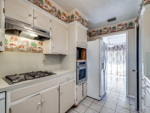 kitchen featuring white cabinetry, appliances with stainless steel finishes, a textured ceiling, and a notable chandelier