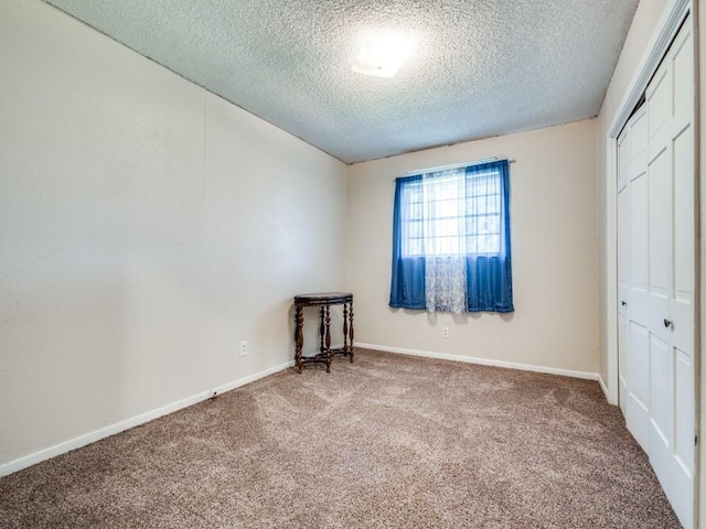 unfurnished bedroom featuring carpet, a textured ceiling, and a closet