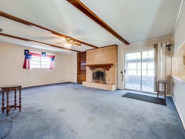 unfurnished living room featuring ceiling fan, beam ceiling, carpet flooring, a fireplace, and a textured ceiling