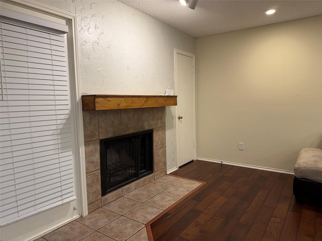 sitting room with wood-type flooring, a fireplace, and a textured ceiling