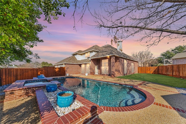 pool at dusk with an in ground hot tub and a yard