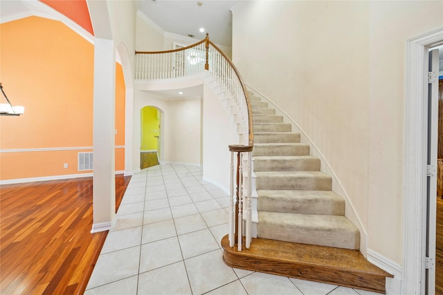 stairway featuring a high ceiling, ornamental molding, and tile patterned flooring