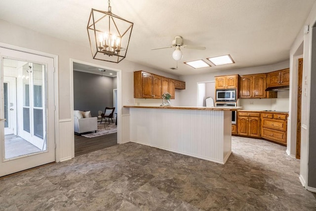 kitchen featuring kitchen peninsula, stove, hanging light fixtures, a breakfast bar, and stainless steel microwave