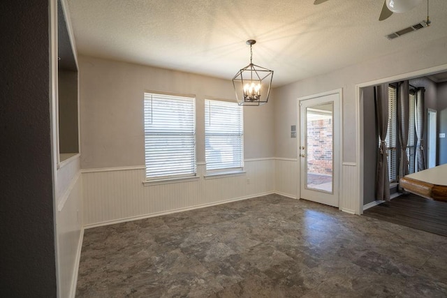 unfurnished room with a textured ceiling and ceiling fan with notable chandelier