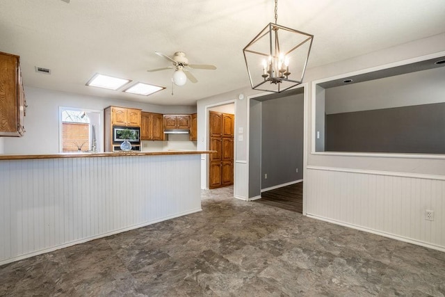 kitchen featuring kitchen peninsula, built in microwave, hanging light fixtures, and ceiling fan