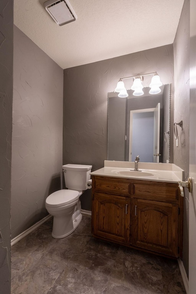 bathroom featuring toilet, a textured ceiling, and vanity