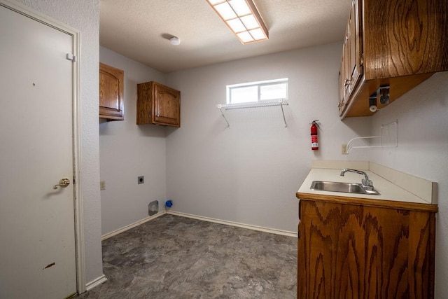 clothes washing area with sink, hookup for an electric dryer, a textured ceiling, and cabinets