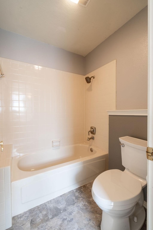 bathroom featuring tiled shower / bath combo and toilet