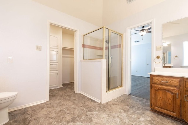 bathroom featuring toilet, ceiling fan, a shower with shower door, and vanity