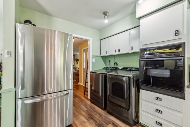 kitchen with stainless steel fridge, hardwood / wood-style floors, washing machine and dryer, white cabinets, and oven