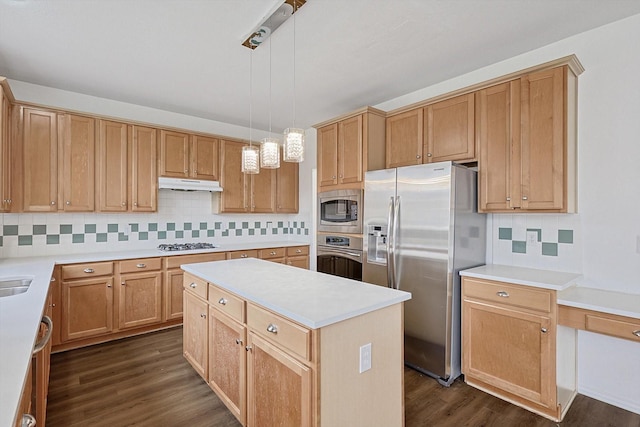 kitchen with appliances with stainless steel finishes, light countertops, a kitchen island, and under cabinet range hood