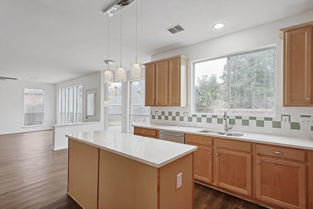 kitchen with light countertops, visible vents, hanging light fixtures, a kitchen island, and a sink