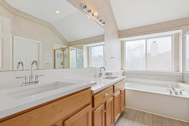 bathroom featuring a stall shower, lofted ceiling, a garden tub, and a sink