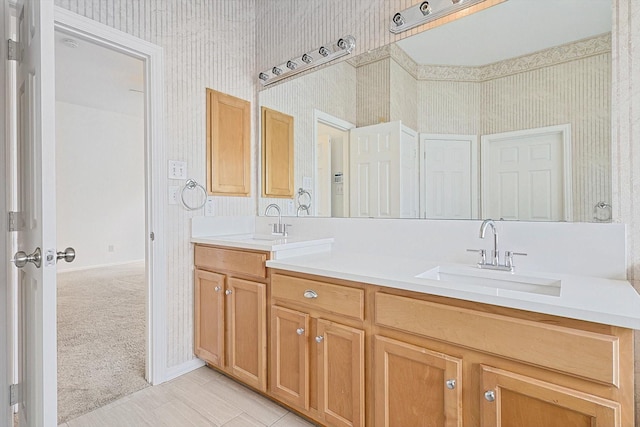 full bathroom with double vanity, a sink, and wallpapered walls