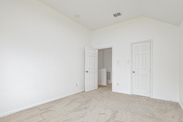 unfurnished bedroom featuring light carpet, lofted ceiling, visible vents, and baseboards