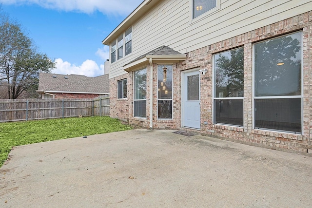 exterior space with a yard, brick siding, a patio area, and fence