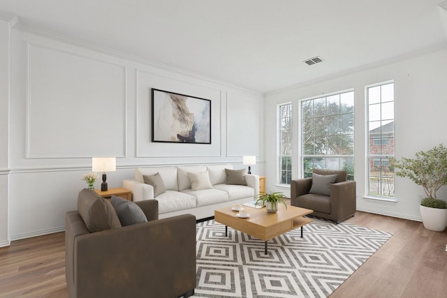 living area featuring light wood-style floors, visible vents, and a decorative wall