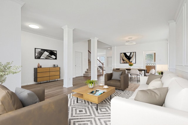 living area featuring ornamental molding, light wood-style floors, ornate columns, and stairs