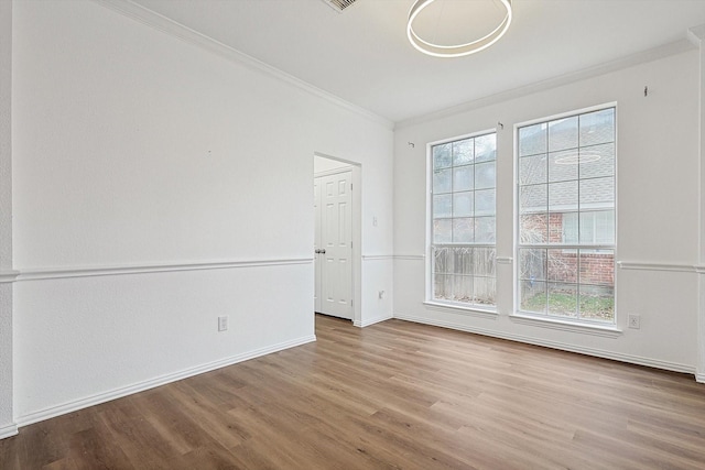 empty room with light wood finished floors, baseboards, and ornamental molding