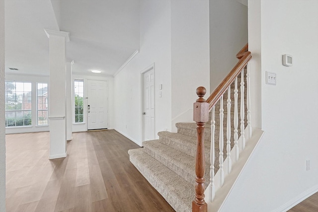 foyer entrance with ornate columns, stairway, wood finished floors, and baseboards