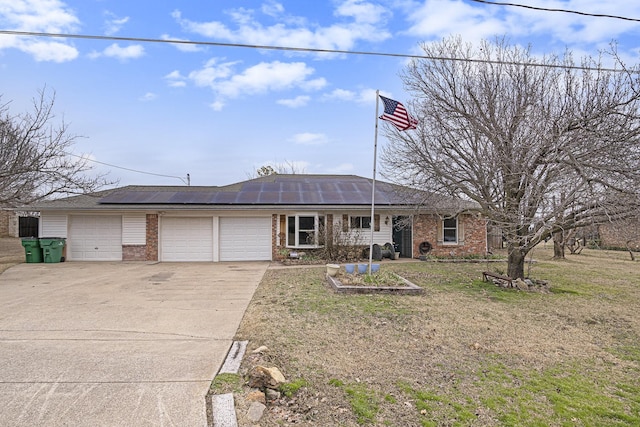 single story home featuring driveway, an attached garage, roof mounted solar panels, a front lawn, and brick siding