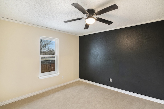 carpeted empty room featuring a textured ceiling, a ceiling fan, crown molding, and baseboards