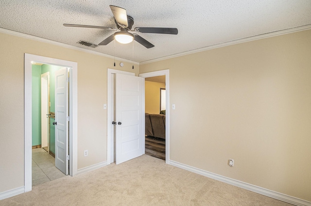unfurnished bedroom featuring ornamental molding, visible vents, light carpet, and baseboards