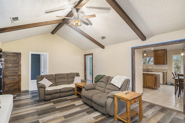 living area featuring visible vents, a ceiling fan, light wood-style floors, and a textured ceiling