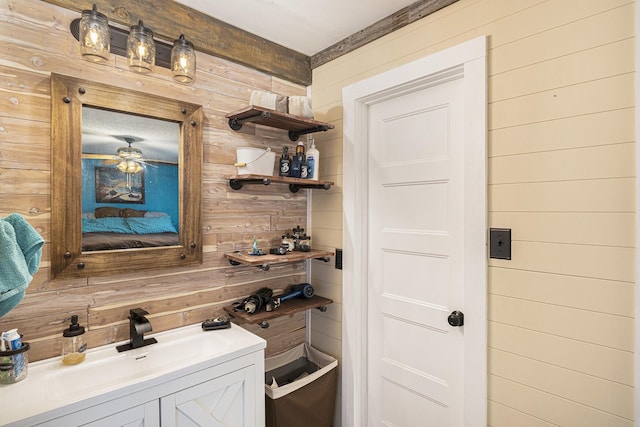 interior space with a sink, ceiling fan, and wood walls