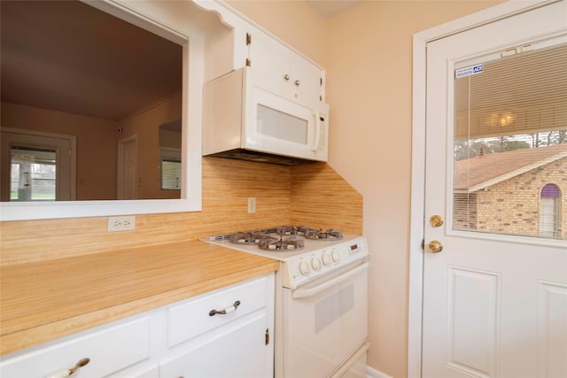 kitchen with tasteful backsplash, white cabinets, and white appliances