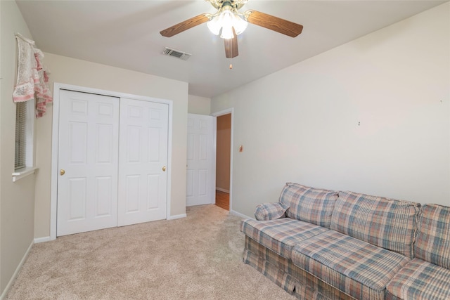 living area featuring light carpet and ceiling fan