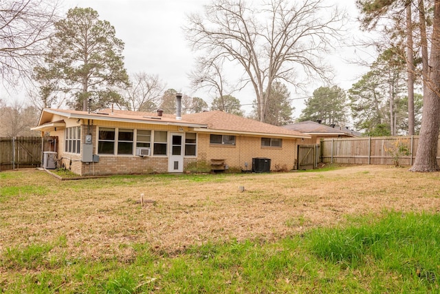 rear view of house with cooling unit, central AC, and a lawn