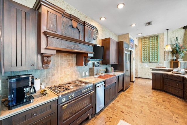 kitchen featuring stainless steel appliances, sink, pendant lighting, and dark brown cabinetry