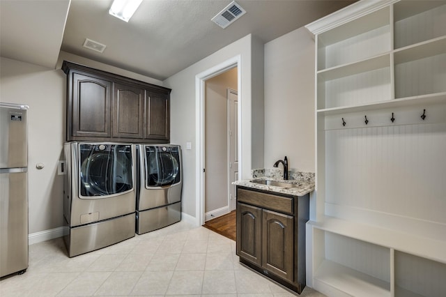 clothes washing area with cabinets, washing machine and clothes dryer, sink, and light tile patterned floors