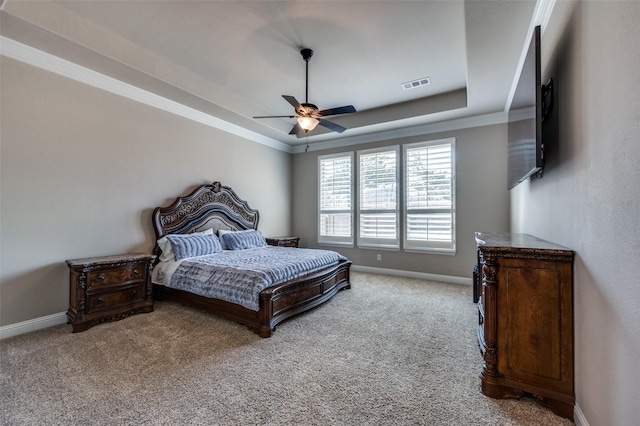 carpeted bedroom featuring crown molding, ceiling fan, and a raised ceiling