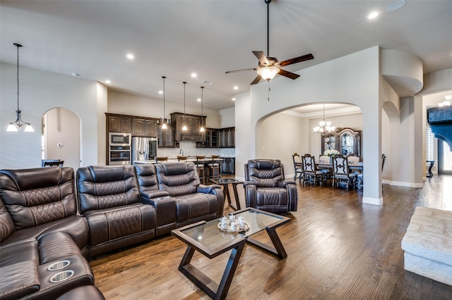 living room featuring a high ceiling, ceiling fan with notable chandelier, and light wood-type flooring