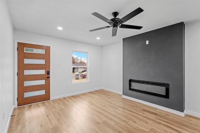 interior space with ceiling fan, a fireplace, and light hardwood / wood-style floors