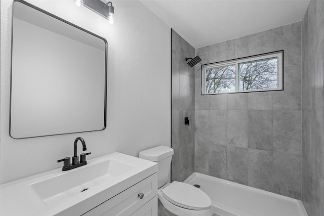 bathroom featuring vanity, toilet, and a tile shower