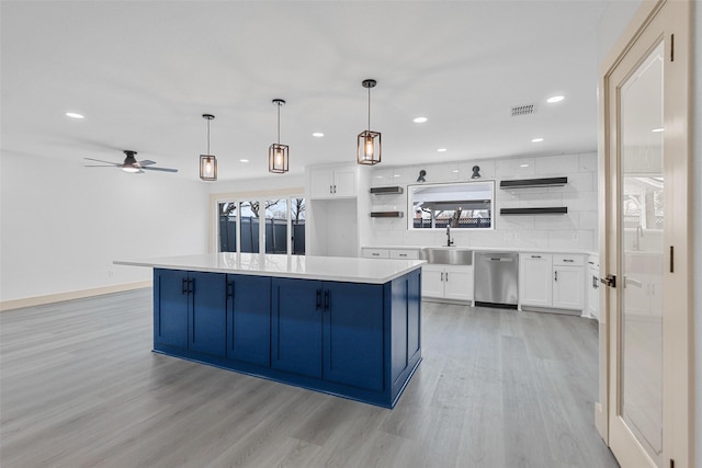 kitchen featuring hanging light fixtures, light countertops, white cabinetry, open shelves, and stainless steel dishwasher