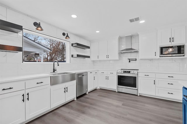 kitchen featuring stainless steel appliances, white cabinetry, light countertops, wall chimney range hood, and open shelves