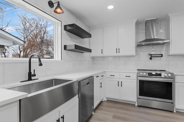 kitchen featuring stainless steel appliances, white cabinets, light countertops, and wall chimney exhaust hood