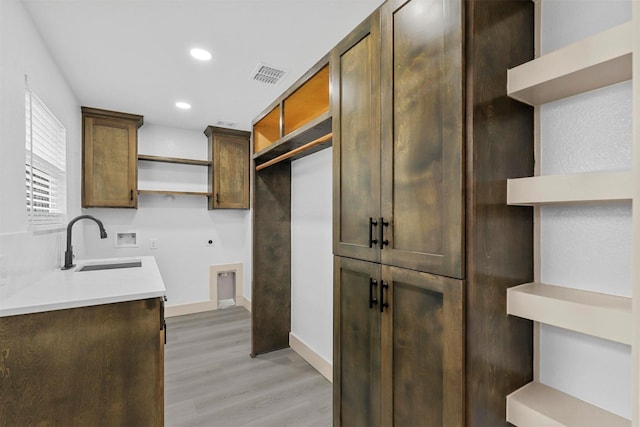 kitchen featuring visible vents, light wood-style flooring, light countertops, open shelves, and a sink