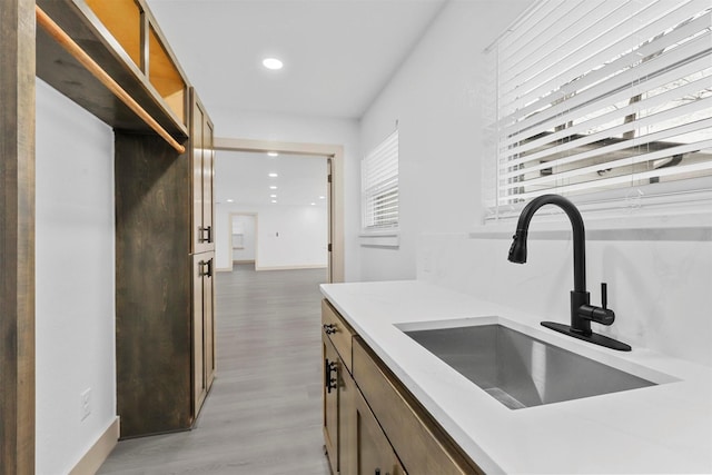 kitchen featuring brown cabinetry, light countertops, light wood-type flooring, a sink, and recessed lighting