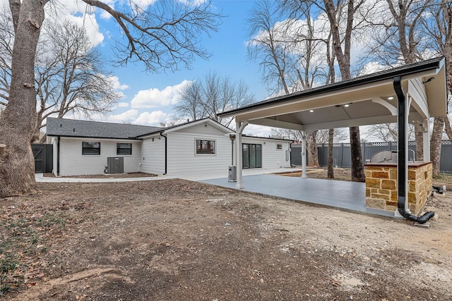 rear view of house with a patio, central AC unit, brick siding, fence, and a carport