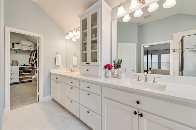 bathroom with vanity, a shower with shower door, and vaulted ceiling