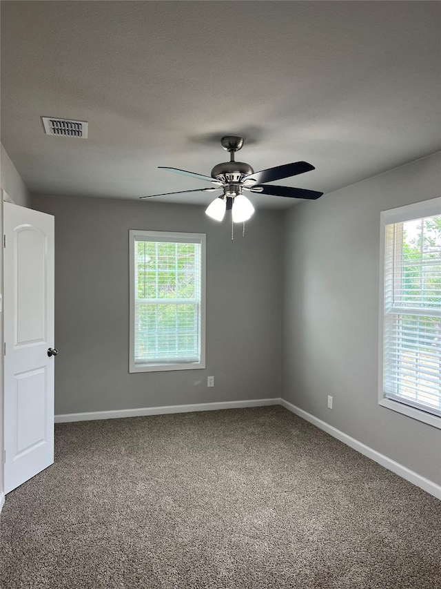 empty room featuring plenty of natural light, ceiling fan, and carpet