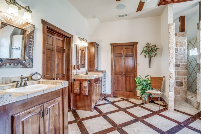 505 Mccormick Rd, Oak Point, TX 75068 - full bathroom with inlaid floor details, two vanities, ceiling fan, vaulted ceiling, and tiled shower