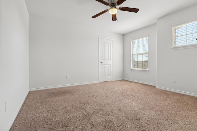 carpeted spare room featuring ceiling fan and baseboards