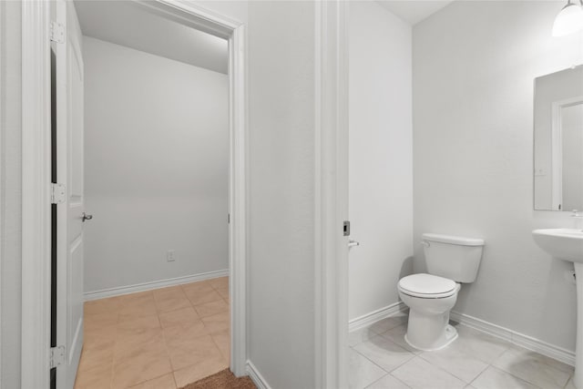 half bath featuring baseboards, toilet, and tile patterned floors