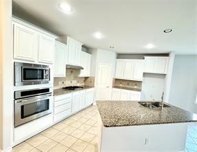 kitchen featuring stainless steel appliances, dark stone countertops, white cabinets, and decorative backsplash